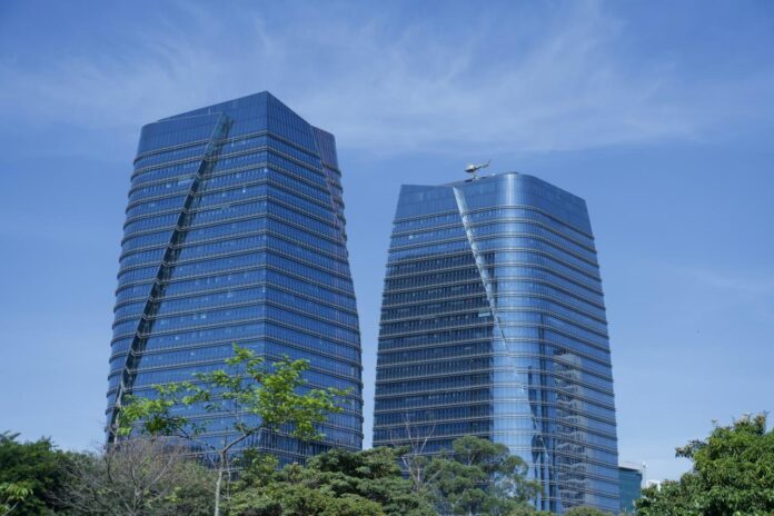 Dua gedung pencakar langit kaca modern dengan langit biru.