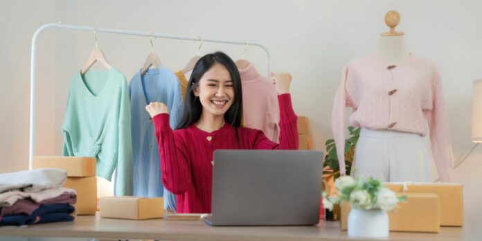 seorang wanita duduk di meja di depan komputer laptop
